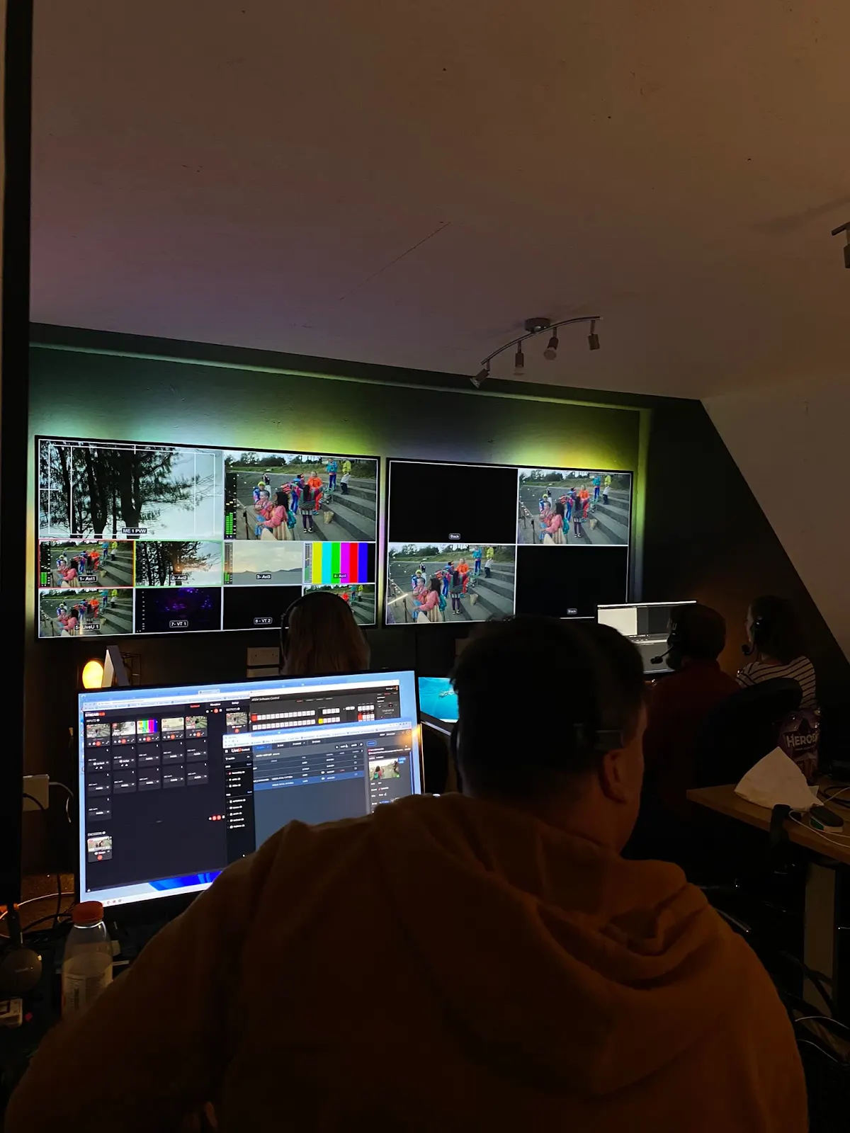 GALWAD production operator at a workstation facing live camera monitors