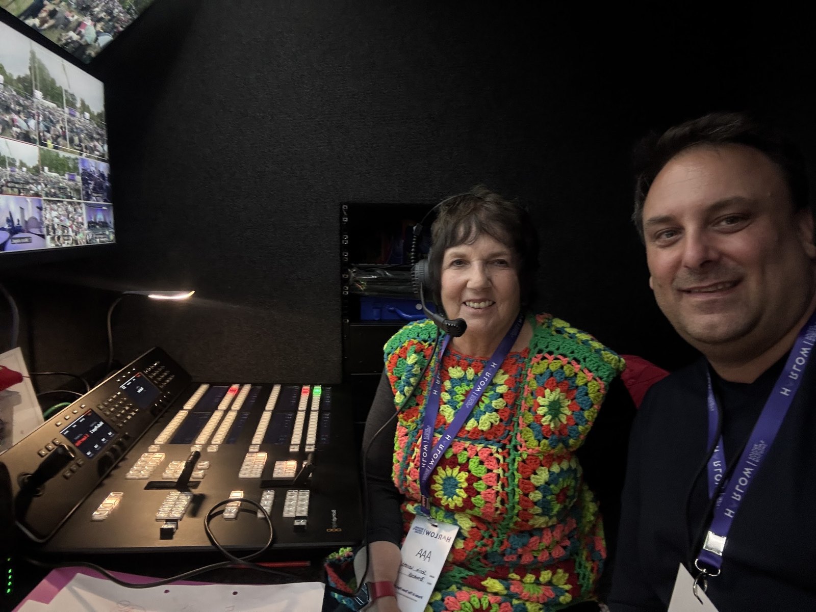 Two smiling production crew members beside a vision mixing desk at Harlow